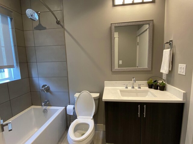 full bathroom featuring vanity, tiled shower / bath combo, and toilet