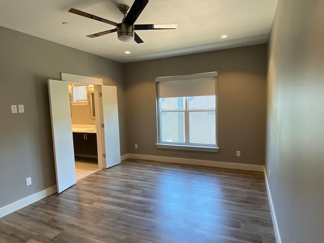 unfurnished bedroom with hardwood / wood-style flooring, ensuite bathroom, and ceiling fan