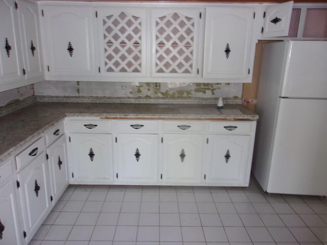 kitchen featuring light tile patterned flooring, white cabinets, and white fridge