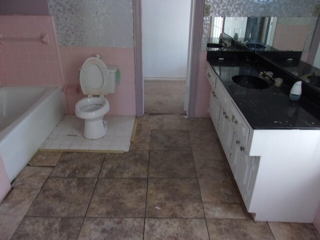 bathroom featuring vanity, a bathing tub, tile patterned flooring, and toilet