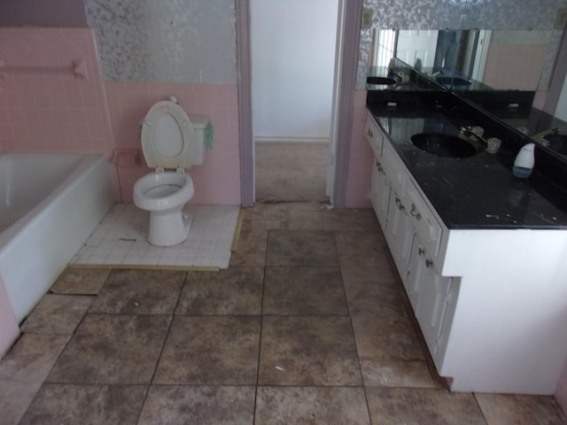bathroom with vanity, a bathing tub, tile patterned flooring, and tile walls