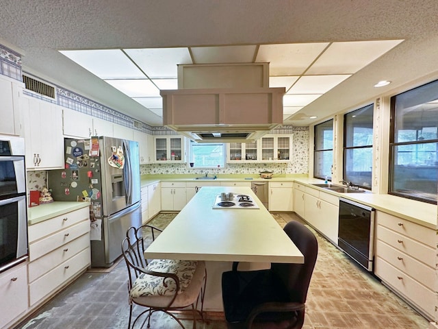 kitchen featuring double wall oven, dishwasher, backsplash, a kitchen island, and sink