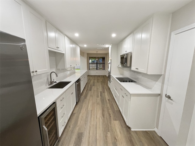 kitchen featuring stainless steel appliances, hardwood / wood-style floors, sink, backsplash, and beverage cooler