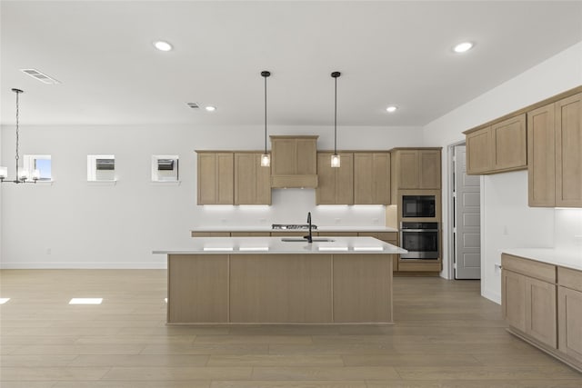 kitchen featuring light hardwood / wood-style floors, stainless steel appliances, decorative light fixtures, an inviting chandelier, and a kitchen island with sink