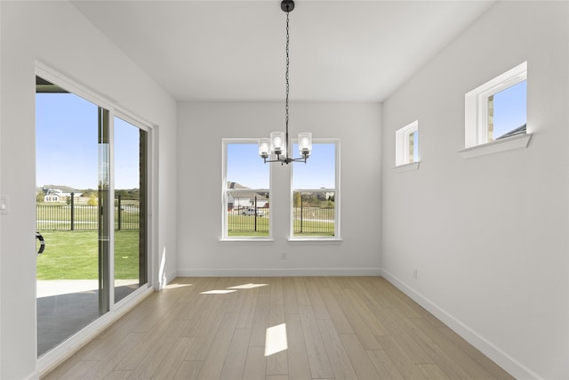 unfurnished dining area featuring a chandelier and light wood-type flooring