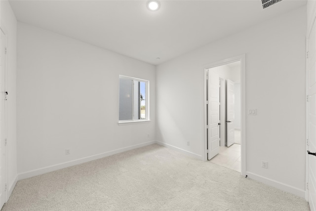 unfurnished bedroom with ensuite bathroom and light colored carpet