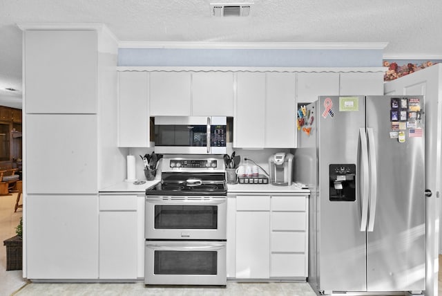 kitchen with crown molding, a textured ceiling, white cabinets, and appliances with stainless steel finishes