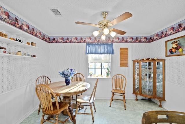 dining space with crown molding, ceiling fan, and a textured ceiling