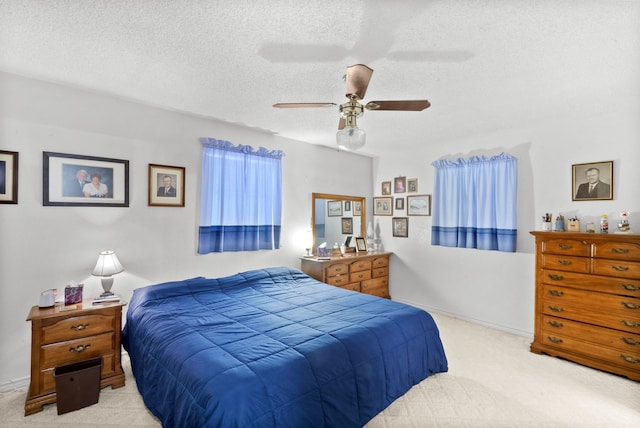 bedroom with ceiling fan, light carpet, and a textured ceiling