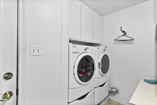 clothes washing area with a textured ceiling, cabinets, and washing machine and clothes dryer