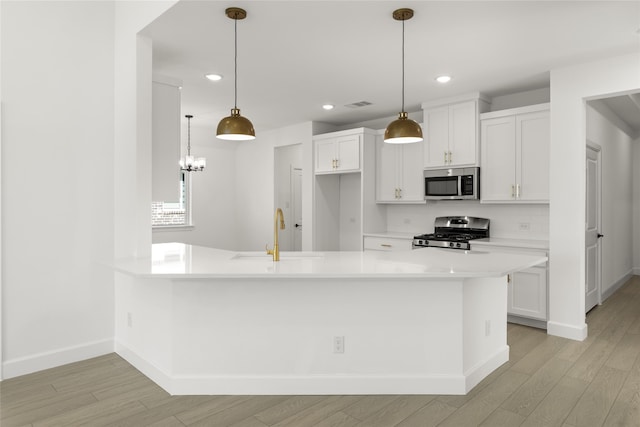 kitchen with appliances with stainless steel finishes, sink, hanging light fixtures, and white cabinets