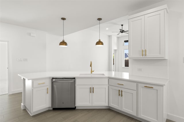 kitchen with sink, dishwasher, white cabinets, decorative light fixtures, and kitchen peninsula