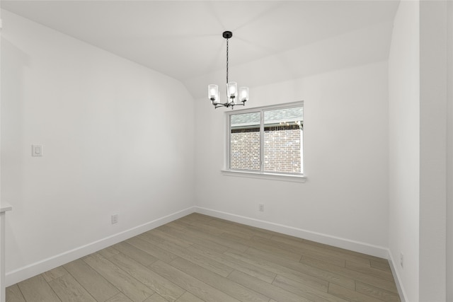 empty room with lofted ceiling, a notable chandelier, and light hardwood / wood-style flooring