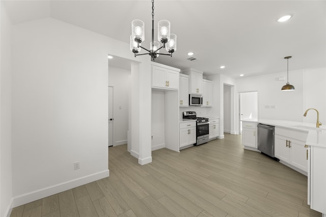 kitchen with sink, stainless steel appliances, white cabinets, decorative light fixtures, and light wood-type flooring