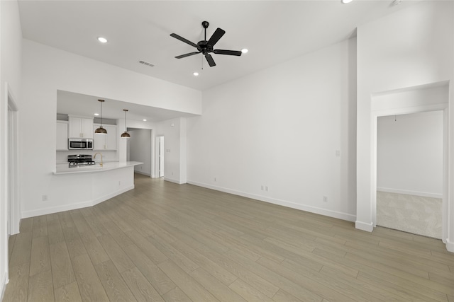 unfurnished living room with ceiling fan and light hardwood / wood-style flooring