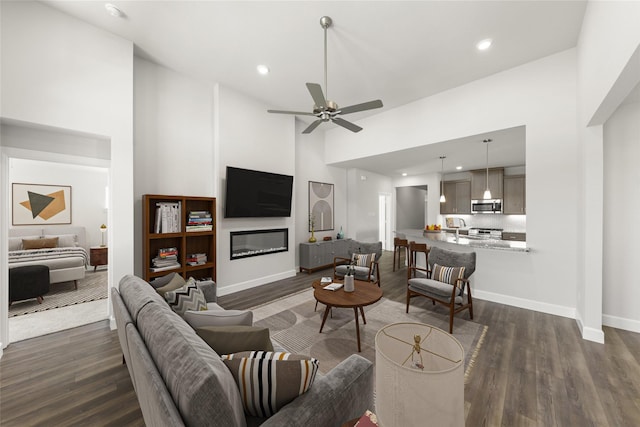 living room featuring dark hardwood / wood-style flooring, ceiling fan, and high vaulted ceiling