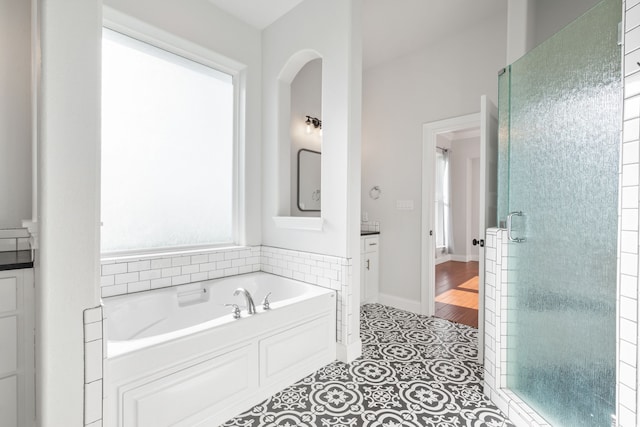 bathroom featuring tile patterned flooring, vanity, and plus walk in shower