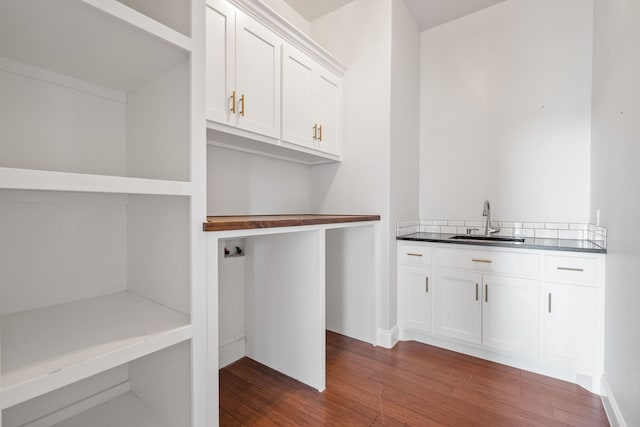 interior space with dark hardwood / wood-style flooring, sink, hookup for a washing machine, and cabinets