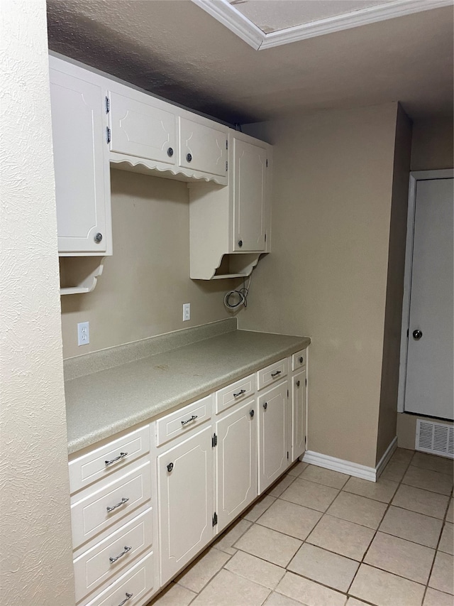 kitchen featuring white cabinets, crown molding, and light tile patterned floors