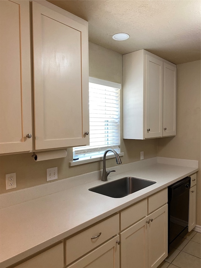 kitchen featuring light tile patterned floors, a textured ceiling, white cabinets, black dishwasher, and sink