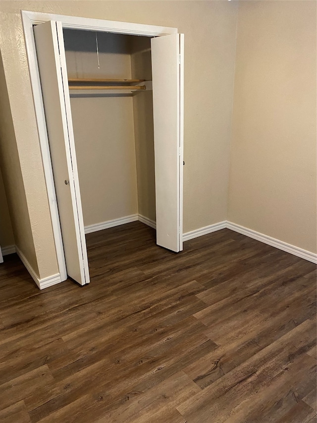 unfurnished bedroom with dark wood-type flooring and a closet