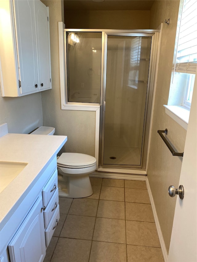 bathroom with tile patterned flooring, walk in shower, toilet, and vanity