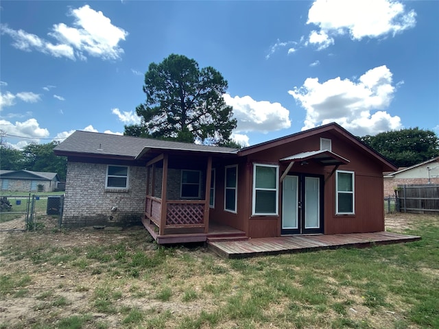 rear view of property with a wooden deck and a lawn