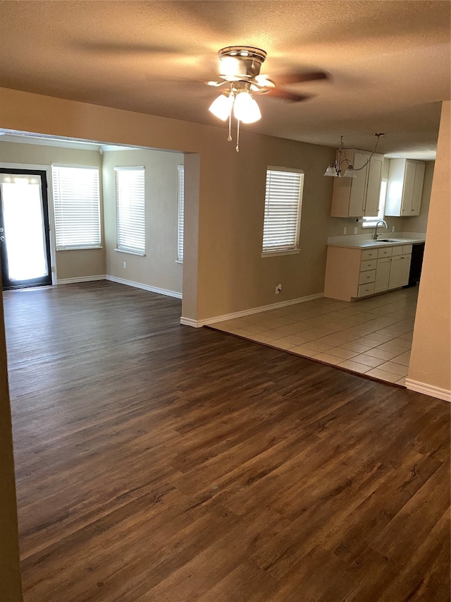 unfurnished living room with sink, a textured ceiling, ceiling fan, and dark wood-type flooring