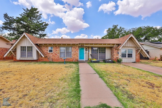 view of front of property with a front yard, brick siding, and board and batten siding