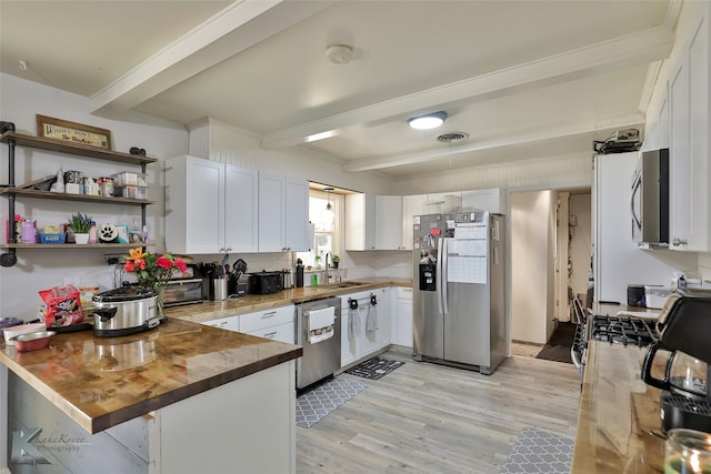 kitchen featuring appliances with stainless steel finishes, light hardwood / wood-style floors, sink, beamed ceiling, and kitchen peninsula