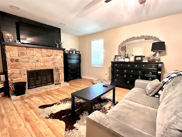 living room featuring hardwood / wood-style flooring, ceiling fan, and a fireplace