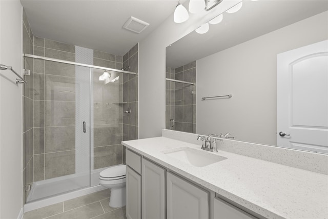 bathroom with tile patterned flooring, vanity, a shower with shower door, and toilet