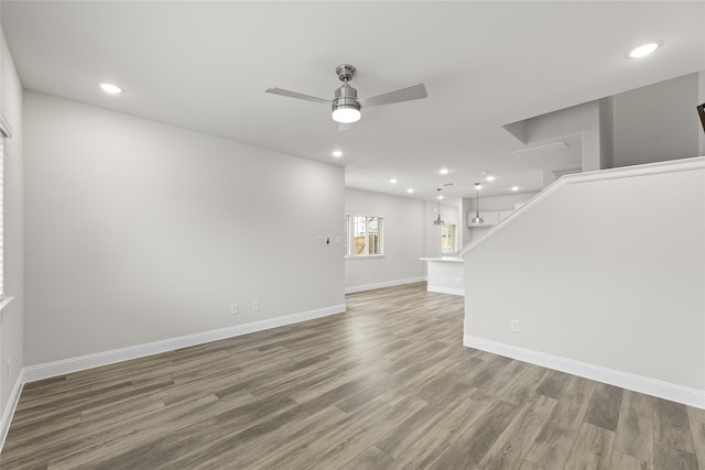 unfurnished living room featuring dark wood-type flooring and ceiling fan