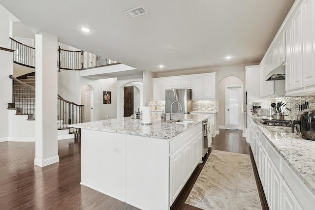 kitchen featuring sink, white cabinetry, dark hardwood / wood-style flooring, an island with sink, and stainless steel appliances