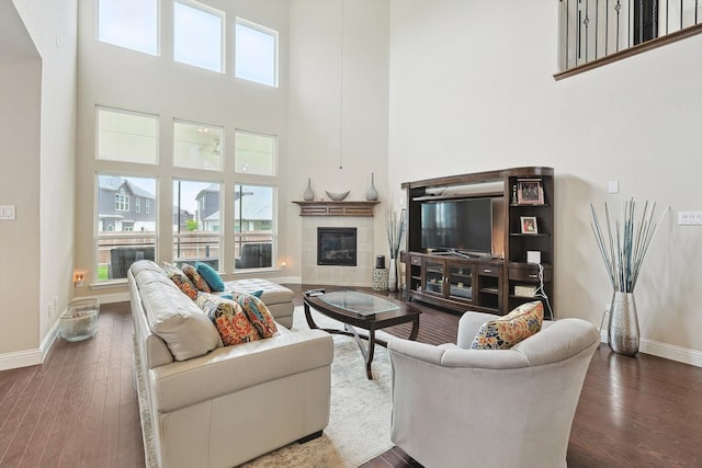 living room featuring a towering ceiling, dark hardwood / wood-style flooring, and a tile fireplace