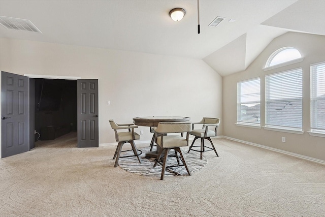 dining space with light colored carpet and vaulted ceiling