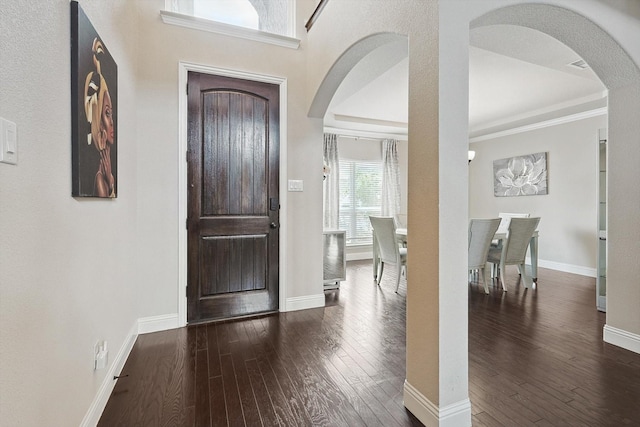 entrance foyer with a raised ceiling, crown molding, and dark hardwood / wood-style floors