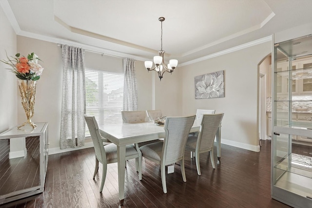 dining space featuring dark hardwood / wood-style flooring, a notable chandelier, a tray ceiling, and crown molding