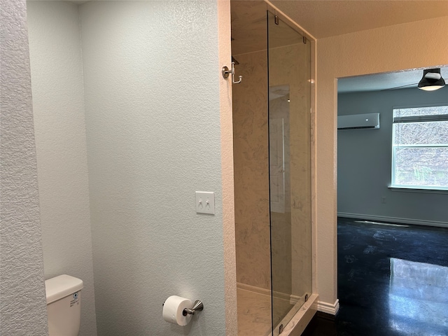 bathroom featuring a shower with shower door, a wall unit AC, and toilet