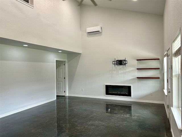 unfurnished living room featuring concrete floors, a wall mounted AC, and a towering ceiling