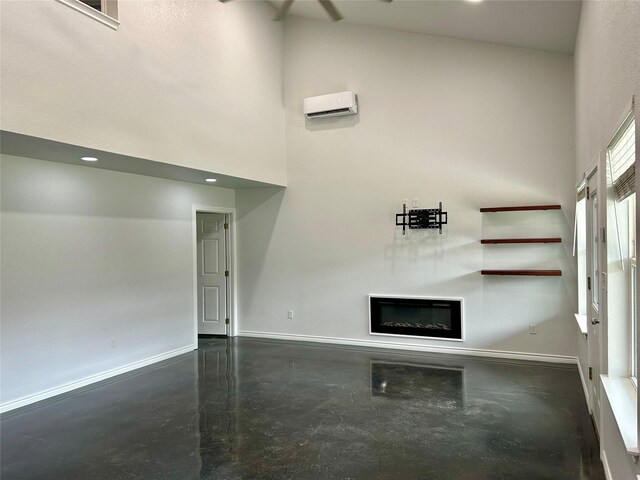 334 Fort Graham Rd, Whitney, TX 76692 - unfurnished living room with a towering ceiling, a glass covered fireplace, baseboards, and finished concrete floors