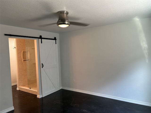 empty room featuring a textured ceiling, a barn door, and ceiling fan