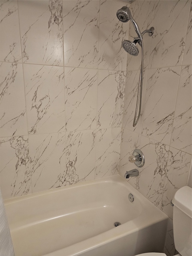 bathroom with tiled shower / bath and toilet