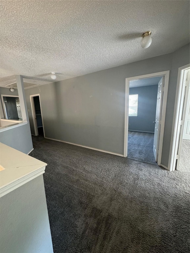 unfurnished living room featuring dark colored carpet and a textured ceiling