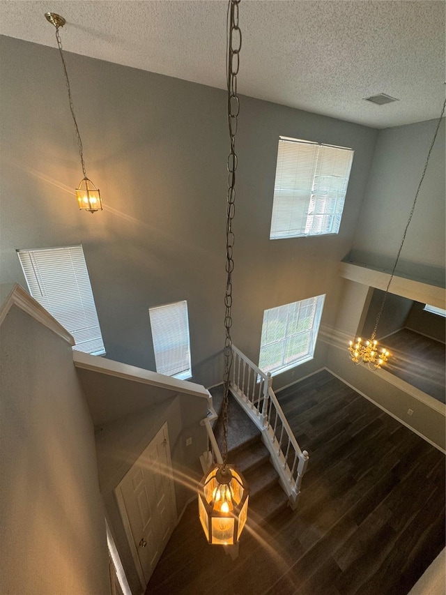 stairs featuring a textured ceiling, hardwood / wood-style flooring, and a notable chandelier