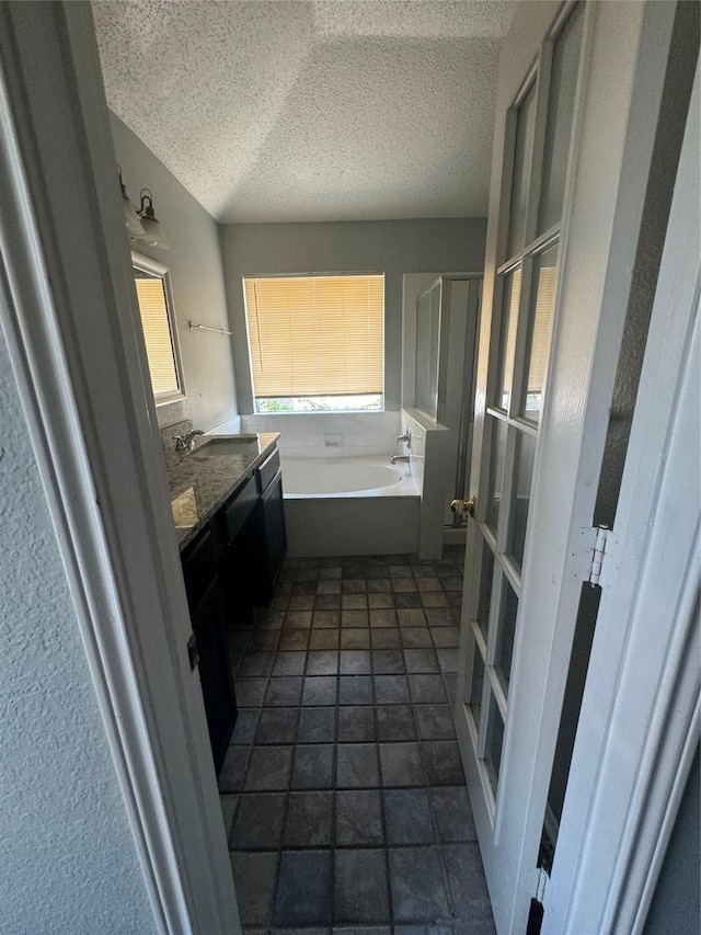 bathroom featuring vanity, a textured ceiling, and a bathtub