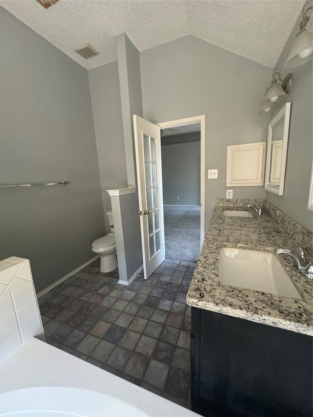 bathroom featuring french doors, a textured ceiling, toilet, and lofted ceiling