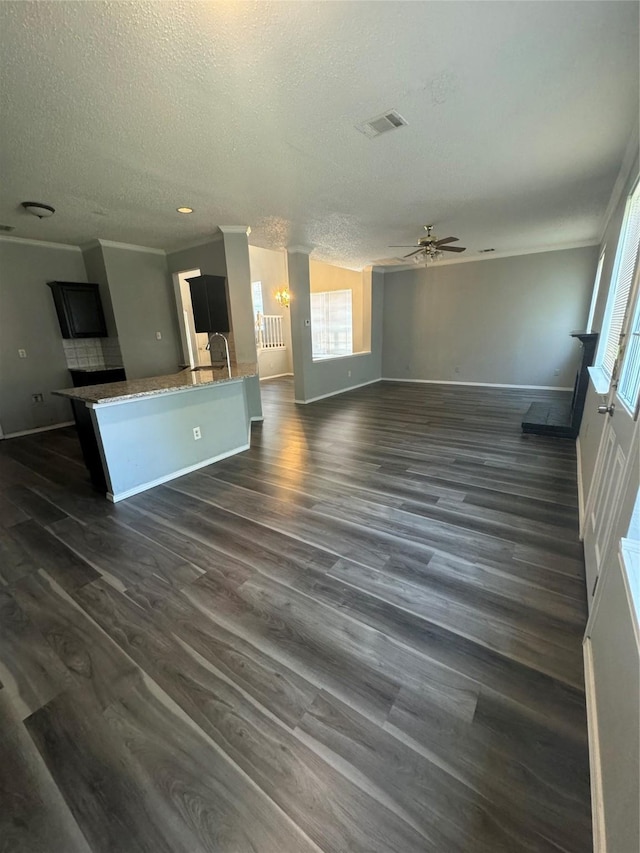 unfurnished living room featuring a textured ceiling, dark hardwood / wood-style flooring, ceiling fan, and ornamental molding