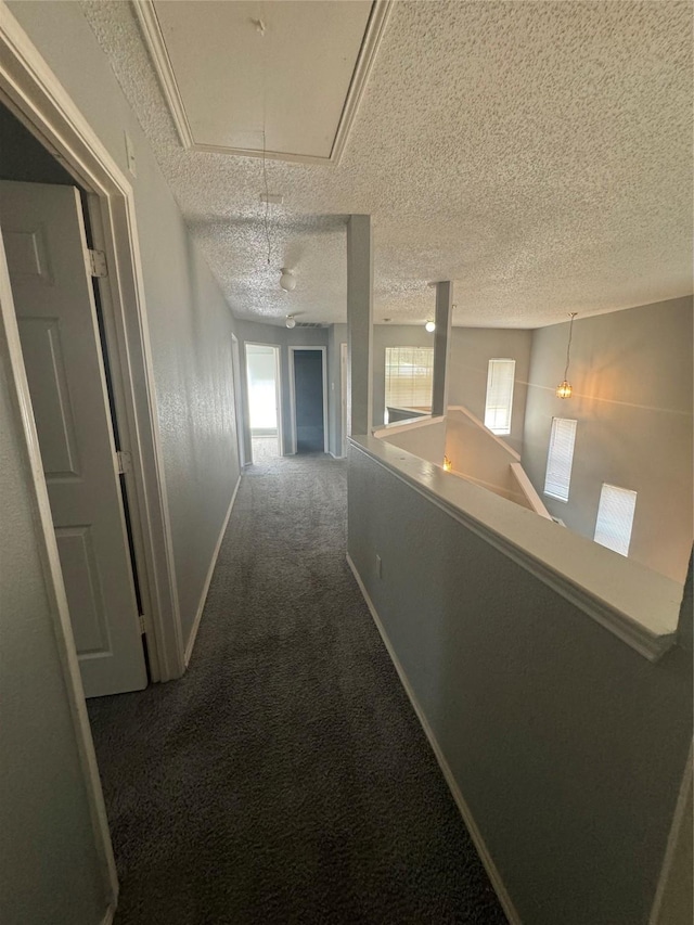 hall with carpet floors, a textured ceiling, and an inviting chandelier