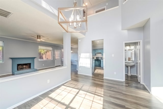 unfurnished living room with plenty of natural light, wood-type flooring, ornamental molding, and a fireplace